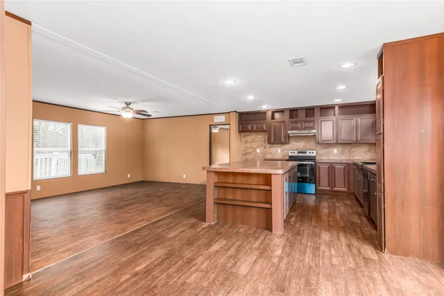 a kitchen with stainless steel appliances kitchen island granite countertop a stove a sink and a refrigerator