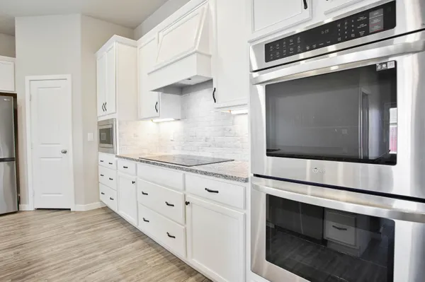 a kitchen with stainless steel appliances granite countertop a stove a sink and white cabinets