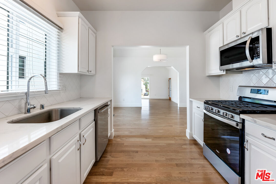 1253 South Rimpau Boulevard Los Angeles, CA 90019 - Photo 50 of 71 a kitchen with stainless steel appliances granite countertop a sink a stove and a microwave