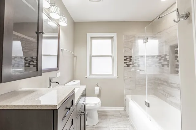 a bathroom with a granite countertop sink toilet and shower