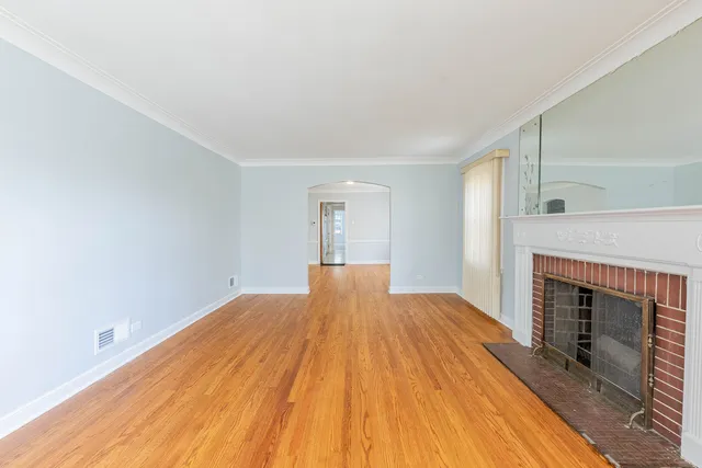 a view of empty room with wooden floor and fireplace