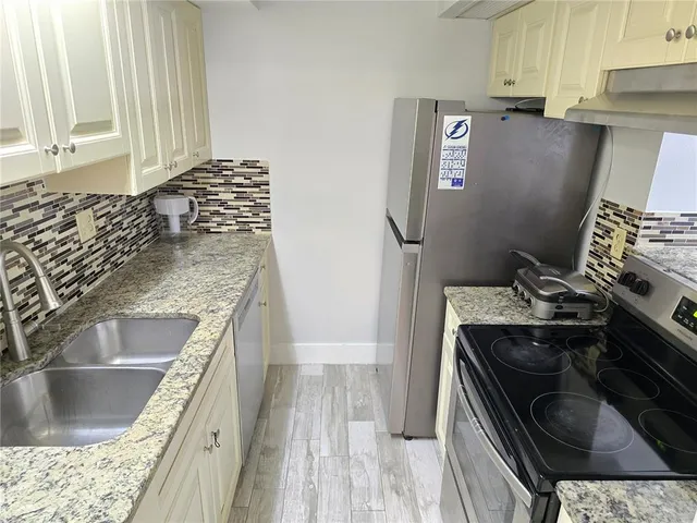 a kitchen with granite countertop a sink stove and refrigerator