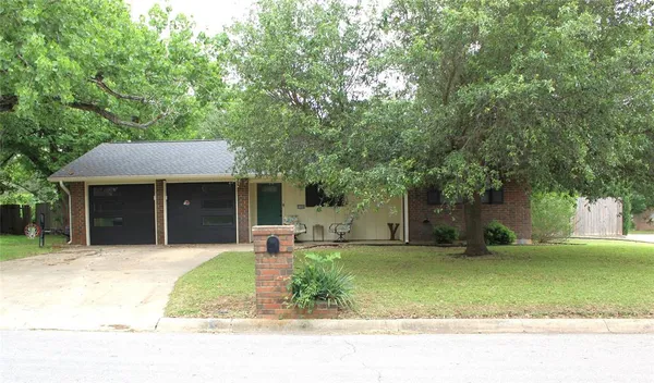 a front view of a house with a garden and tree
