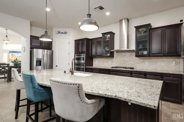 a kitchen with stainless steel appliances granite countertop a sink a stove and a refrigerator