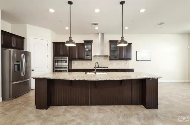 a large kitchen with stainless steel appliances kitchen island granite countertop a stove a sink a oven and a wooden cabinets