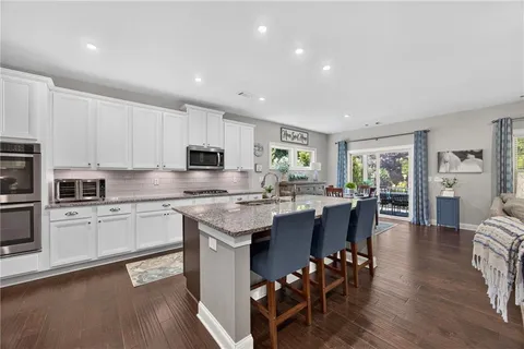 a kitchen with stainless steel appliances granite countertop a table chairs sink refrigerator and cabinets