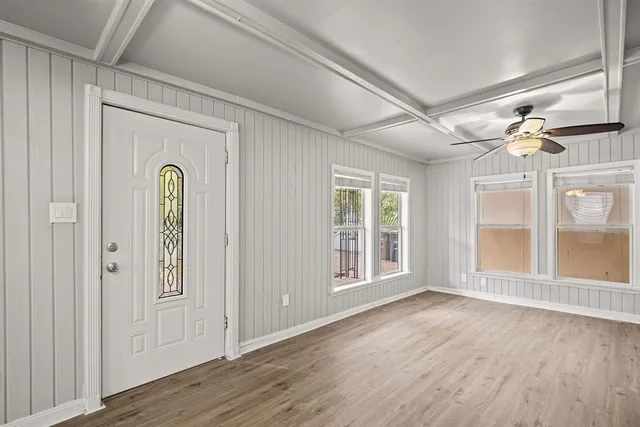 a view of an empty room with a window and wooden floor