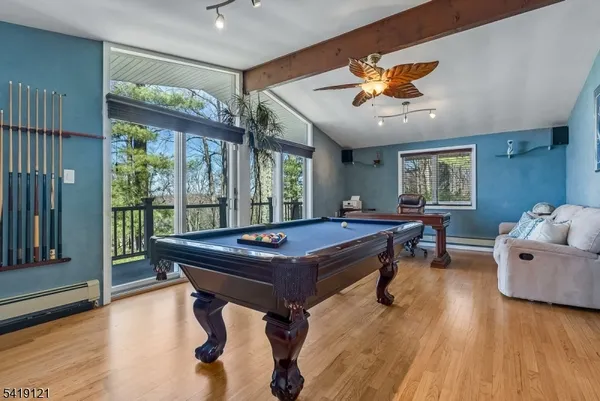a room with furniture pool table wooden floor and windows