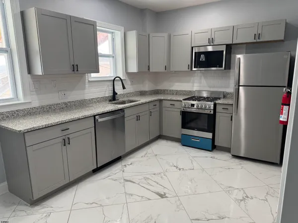 a kitchen with stainless steel appliances granite countertop a sink a stove a refrigerator a microwave and cabinets