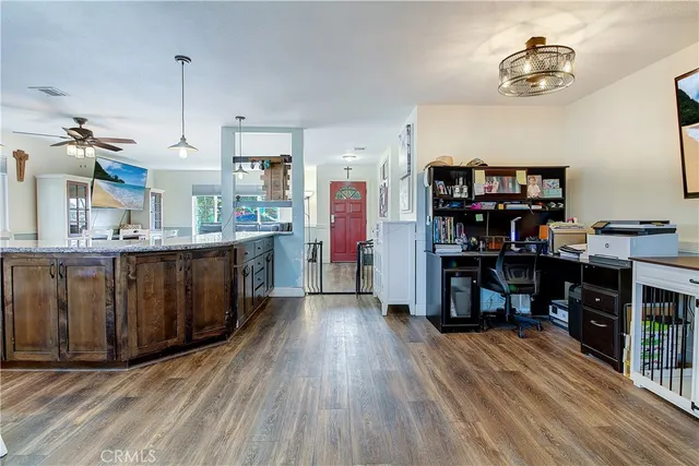 a kitchen with stainless steel appliances kitchen island granite countertop a refrigerator a stove and a wooden floors