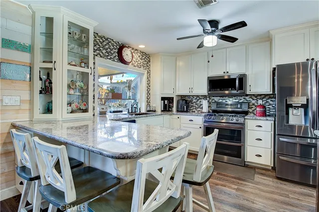 a kitchen with stainless steel appliances granite countertop a kitchen island a stove a table and a refrigerator