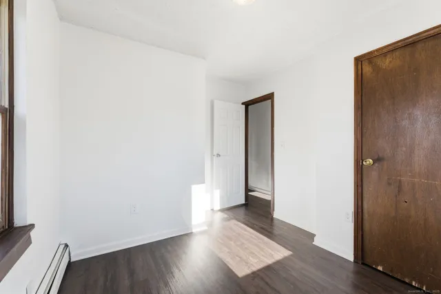 an empty room with wooden floor and entrance