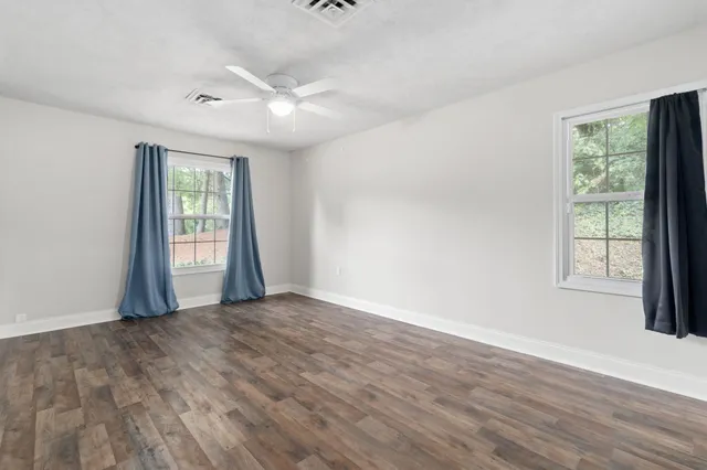 an empty room with wooden floor and windows