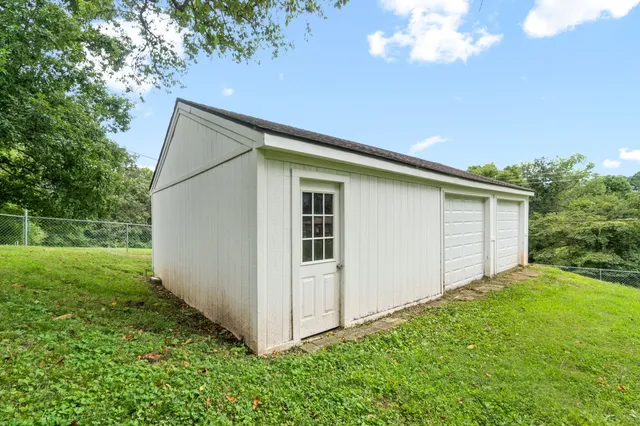 a backyard of a house with plants and large tree