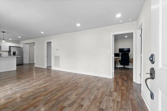 a view of a hallway with wooden floor and a bathroom