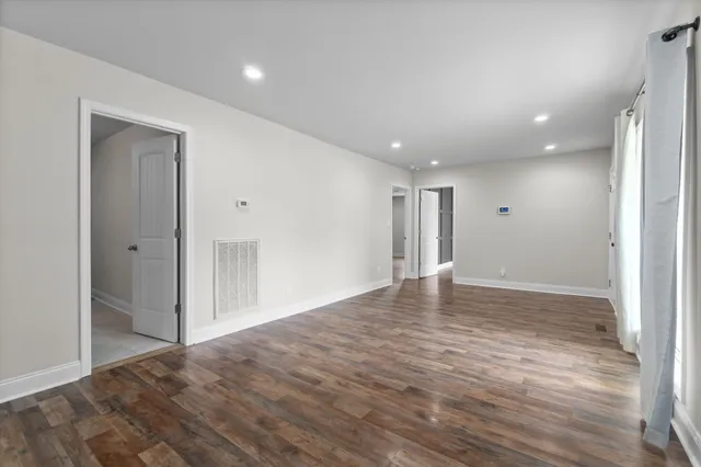 a view of an empty room with wooden floor and a bathroom