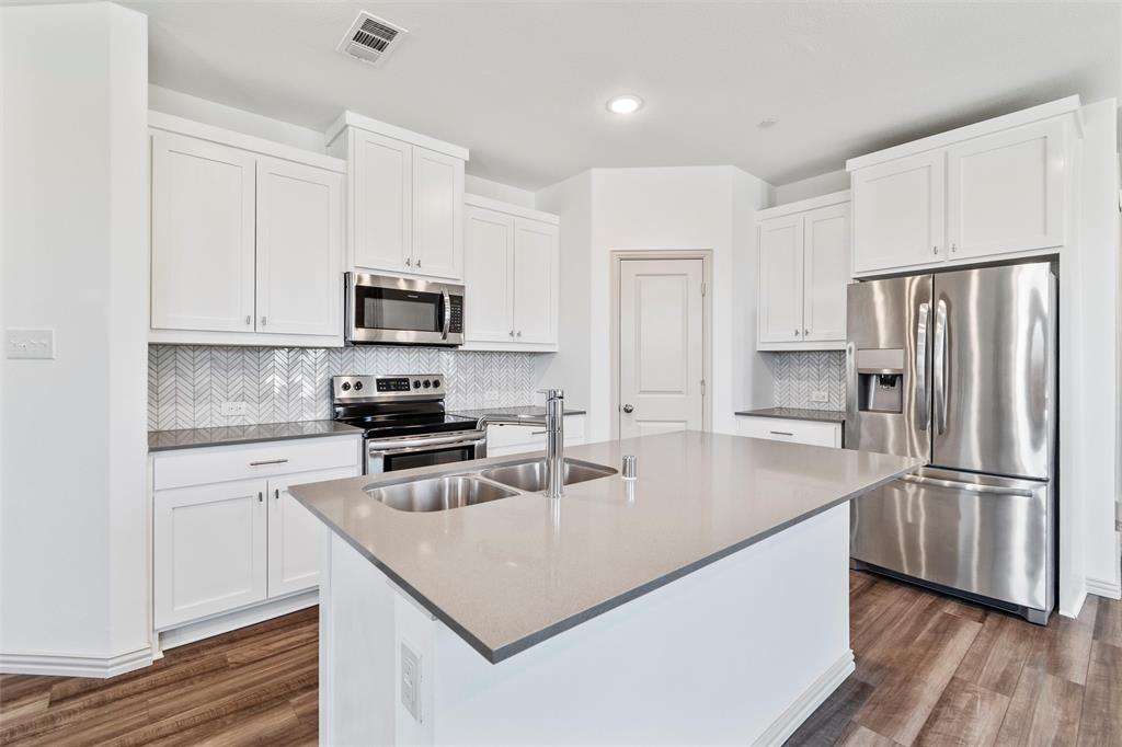 a kitchen with kitchen island a white counter top space stainless steel appliances and wooden floor