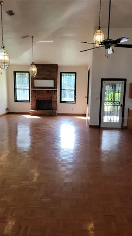 an empty room with wooden floor fireplace and windows