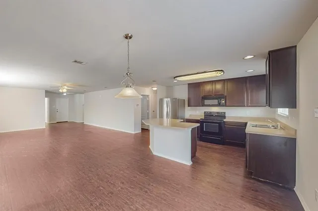 a open kitchen with stainless steel appliances granite countertop a sink dishwasher a stove and a refrigerator with wooden floor