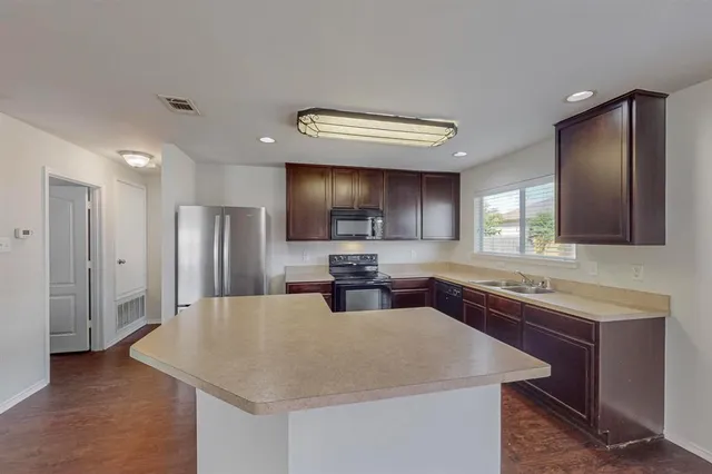 a kitchen with stainless steel appliances granite countertop a sink dishwasher a refrigerator and a stove with wooden floor