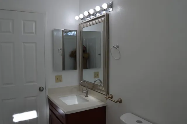 a bathroom with a granite countertop sink a toilet and shower