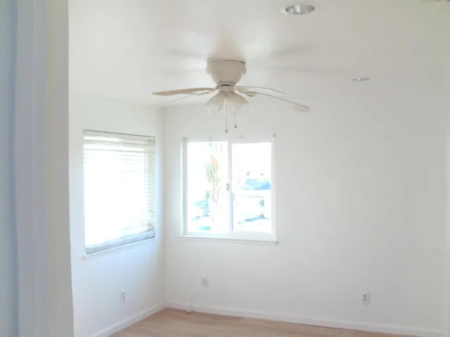 an empty room with a window and a ceiling fan