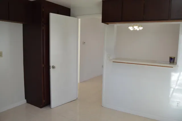 a view of an empty room with wooden floor fireplace and a window