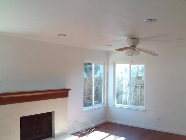 an empty room with windows and fireplace