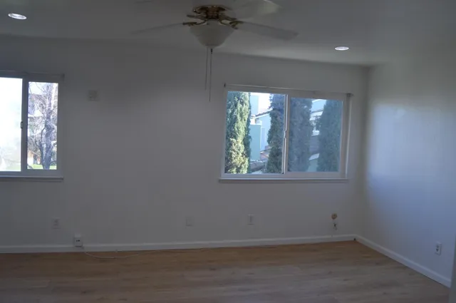 an empty room with windows and fan