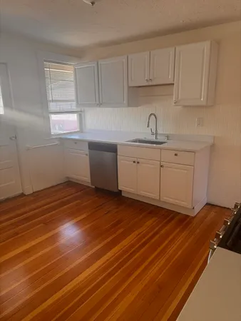 a kitchen with granite countertop white cabinets stainless steel appliances a sink and a window