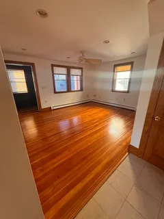 a view of an empty room with wooden floor and a window