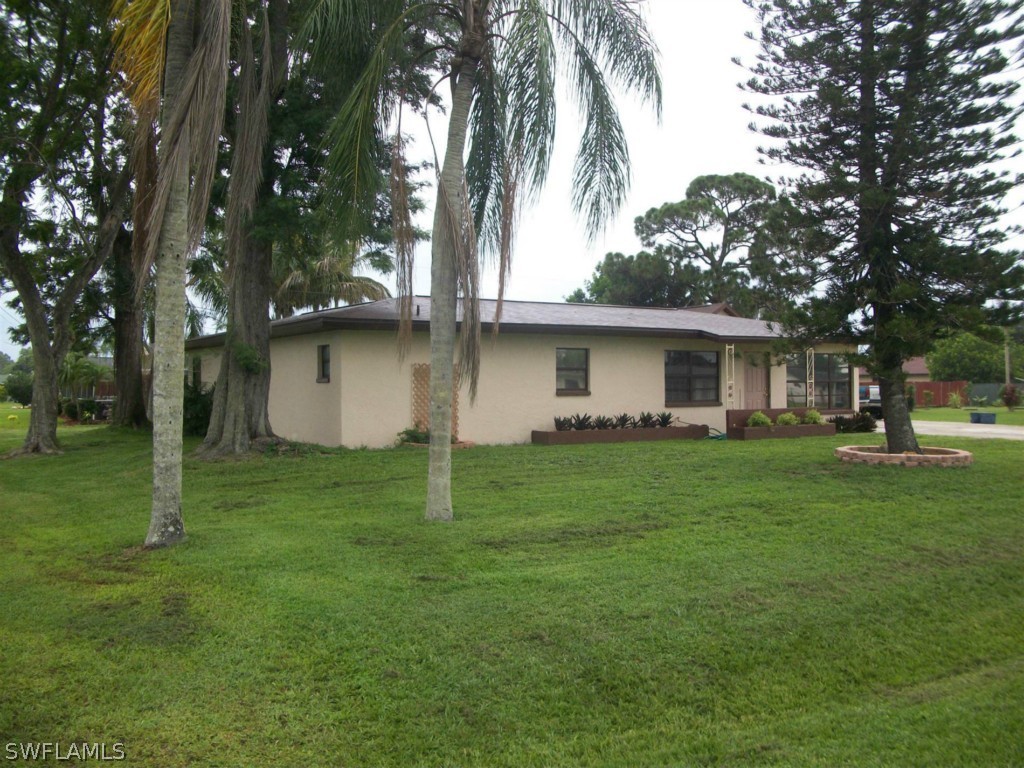 112 Florida Road Lehigh Acres, FL 33936 - Photo 2 of 25 a backyard of a house with plants and large tree