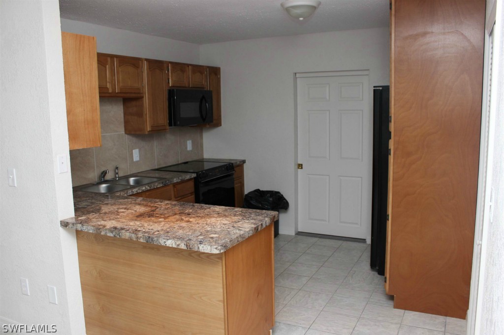 112 Florida Road Lehigh Acres, FL 33936 - Photo 3 of 25 a kitchen with a sink and a refrigerator