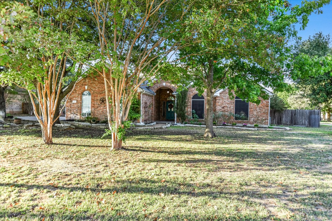 View of property hidden behind natural elements featuring brick siding