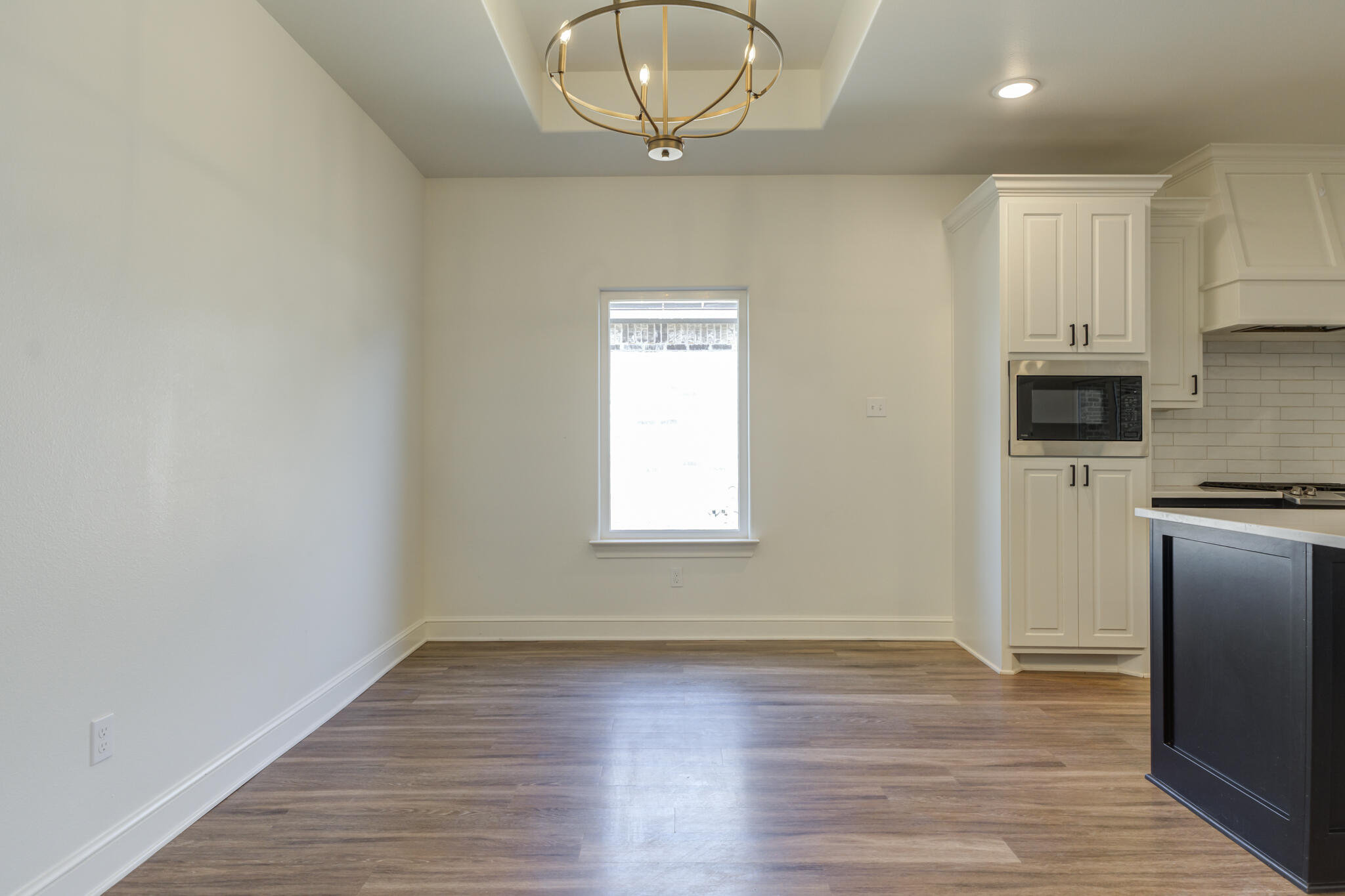 5720 119th Street Lubbock, TX 79424 - Photo 26 of 43 an empty room with wooden floor a kitchen view and a window