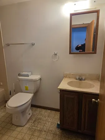 a bathroom with a toilet a sink and mirror