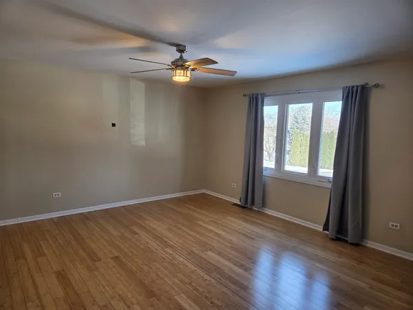 a view of an empty room with a window and wooden floor