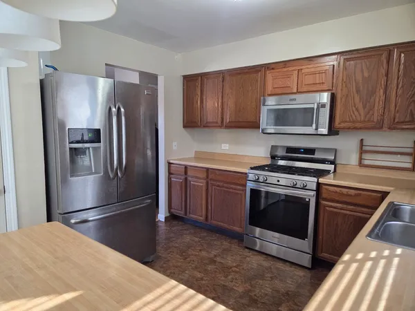 a kitchen with granite countertop a refrigerator and a stove top oven