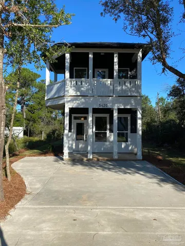 a view of a house with street that has a tree on the side of it