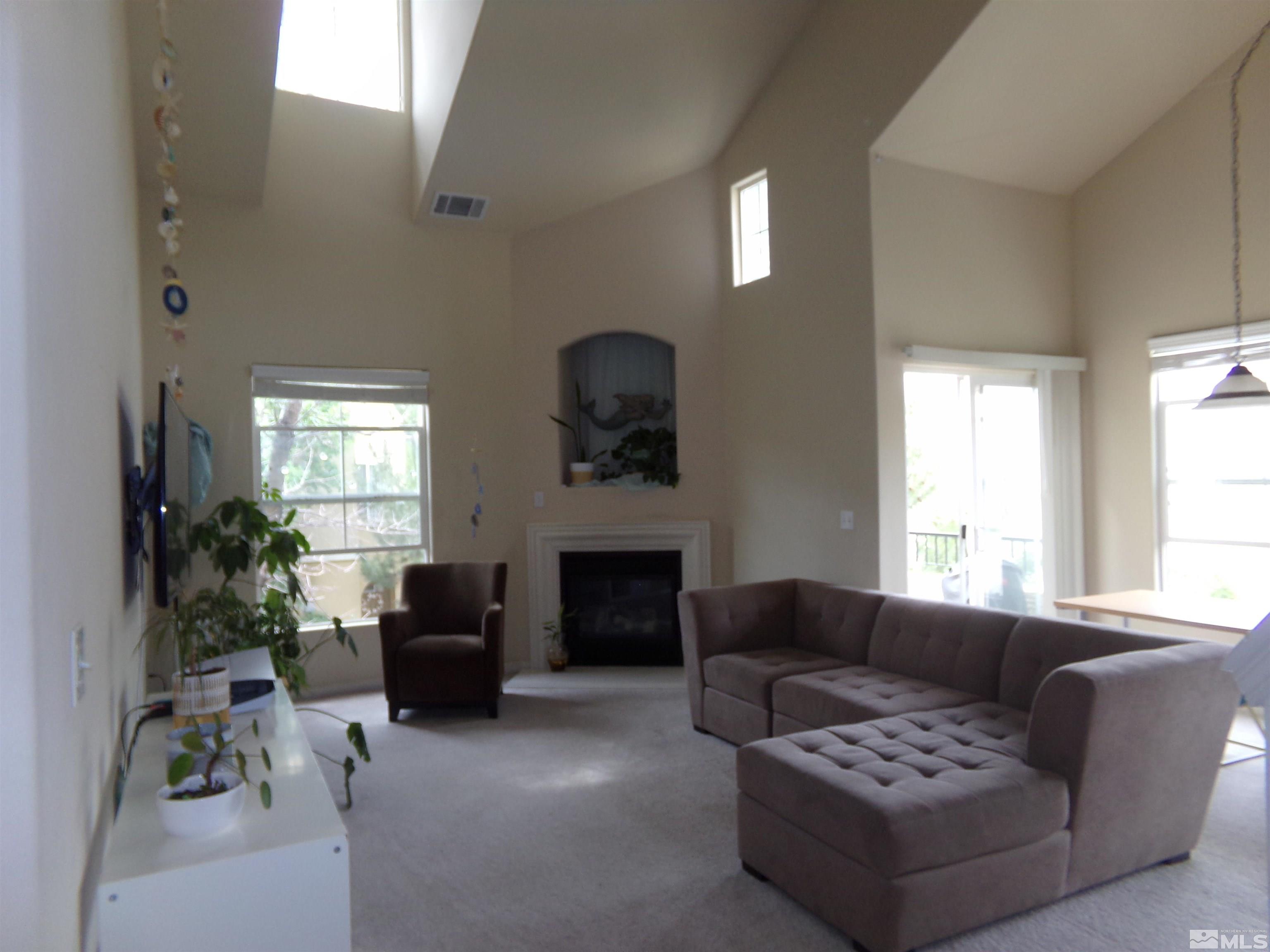 9050 Double R Boulevard, Unit 1124 Reno, NV 89521 - Photo 11 of 40 a living room with furniture a potted plant and a fireplace