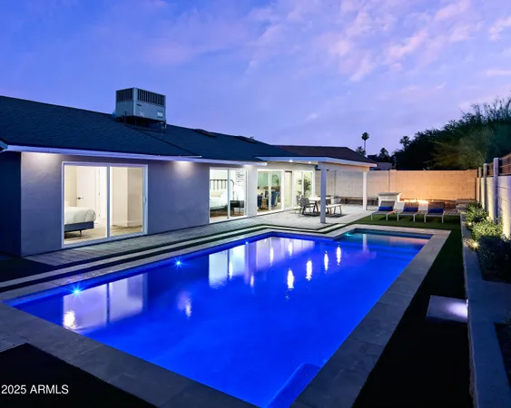 a view of a pool with a dining table chairs in front of it
