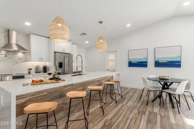 a kitchen with stainless steel appliances a dining table chairs and wooden floor