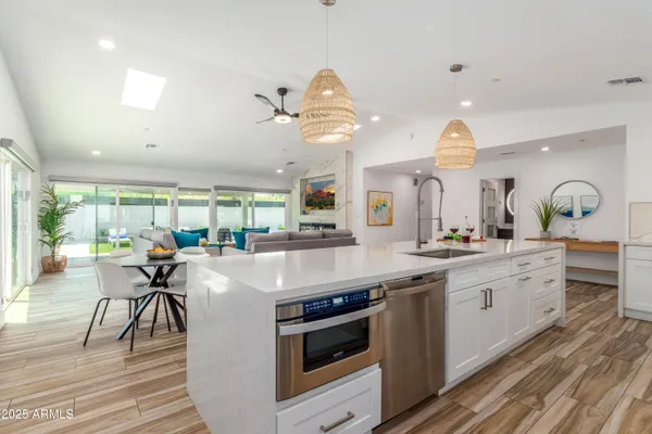 a kitchen with kitchen island granite countertop a stove a sink a dining table and chairs with wooden floor