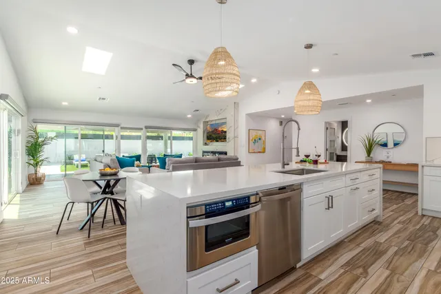 a kitchen with kitchen island granite countertop a stove a sink a dining table and chairs with wooden floor