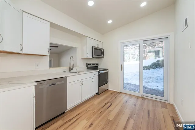 a kitchen with a sink window and stainless steel appliances