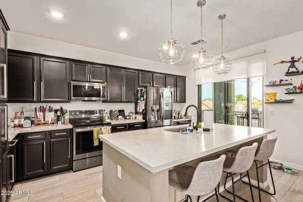 a kitchen with stainless steel appliances kitchen island granite countertop a sink a stove a dining table and chairs