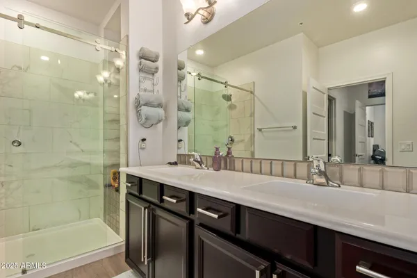 a bathroom with a double vanity sink a mirror and a shower