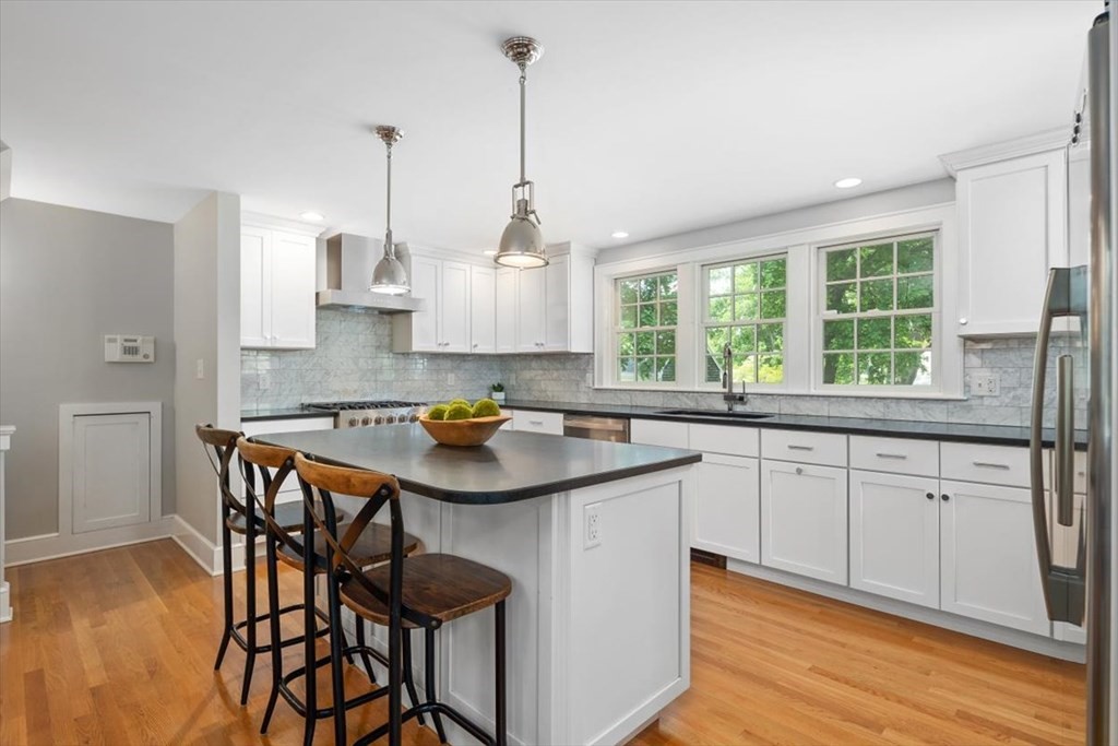 8 Merrymount Road Hingham, MA 02043 - Photo 14 of 34 a kitchen with stainless steel appliances granite countertop a stove a sink a microwave a dining table and chairs with wooden floor