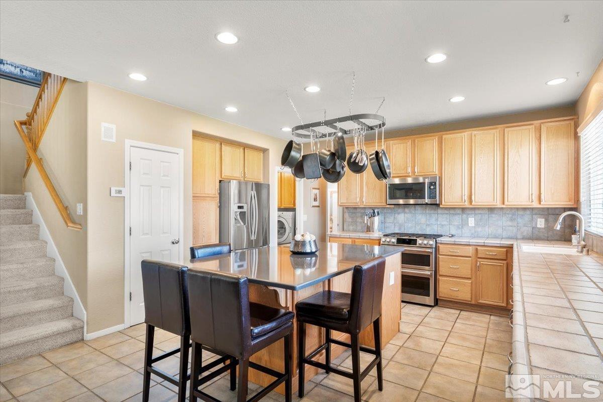 2225 Solitude Drive Reno, NV 89511 - Photo 7 of 40 a kitchen with stainless steel appliances granite countertop a stove a refrigerator a sink a dining table and chairs