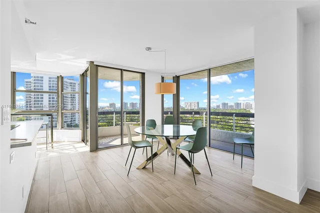 a living room with stainless steel appliances kitchen island granite countertop a refrigerator a stove and a wooden floors